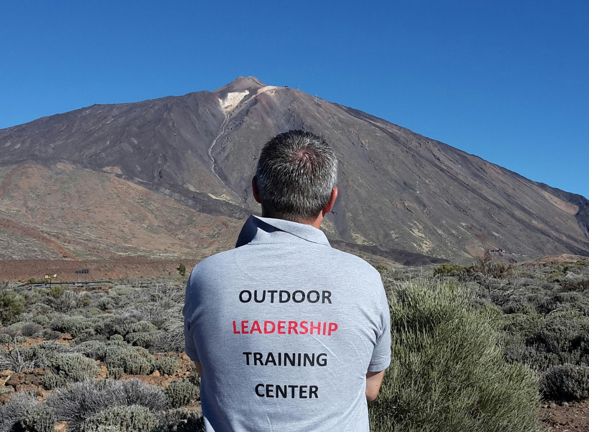 Mads Cronquist set bagfra foran et bjerg med Outdoor Leadership Training Center på ryggen